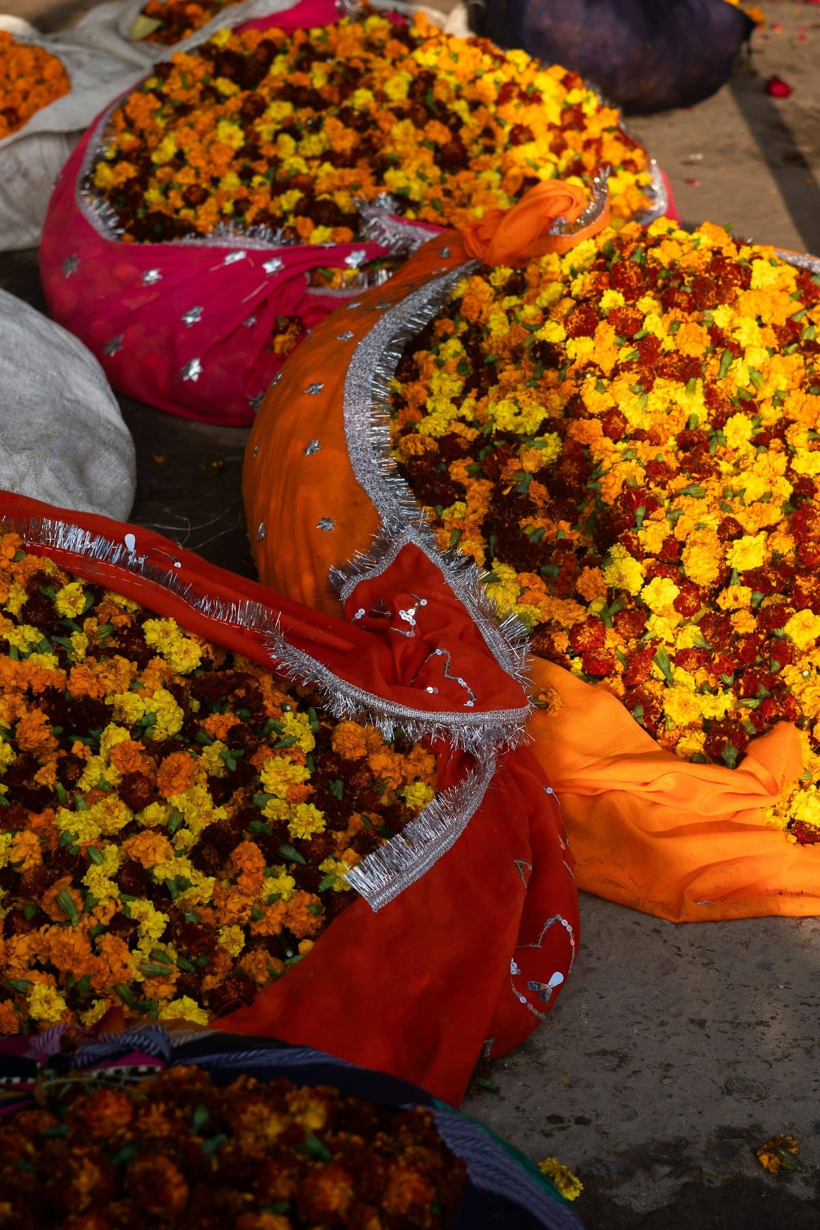 Loose marigolds and other flowers in sacks at a flower market