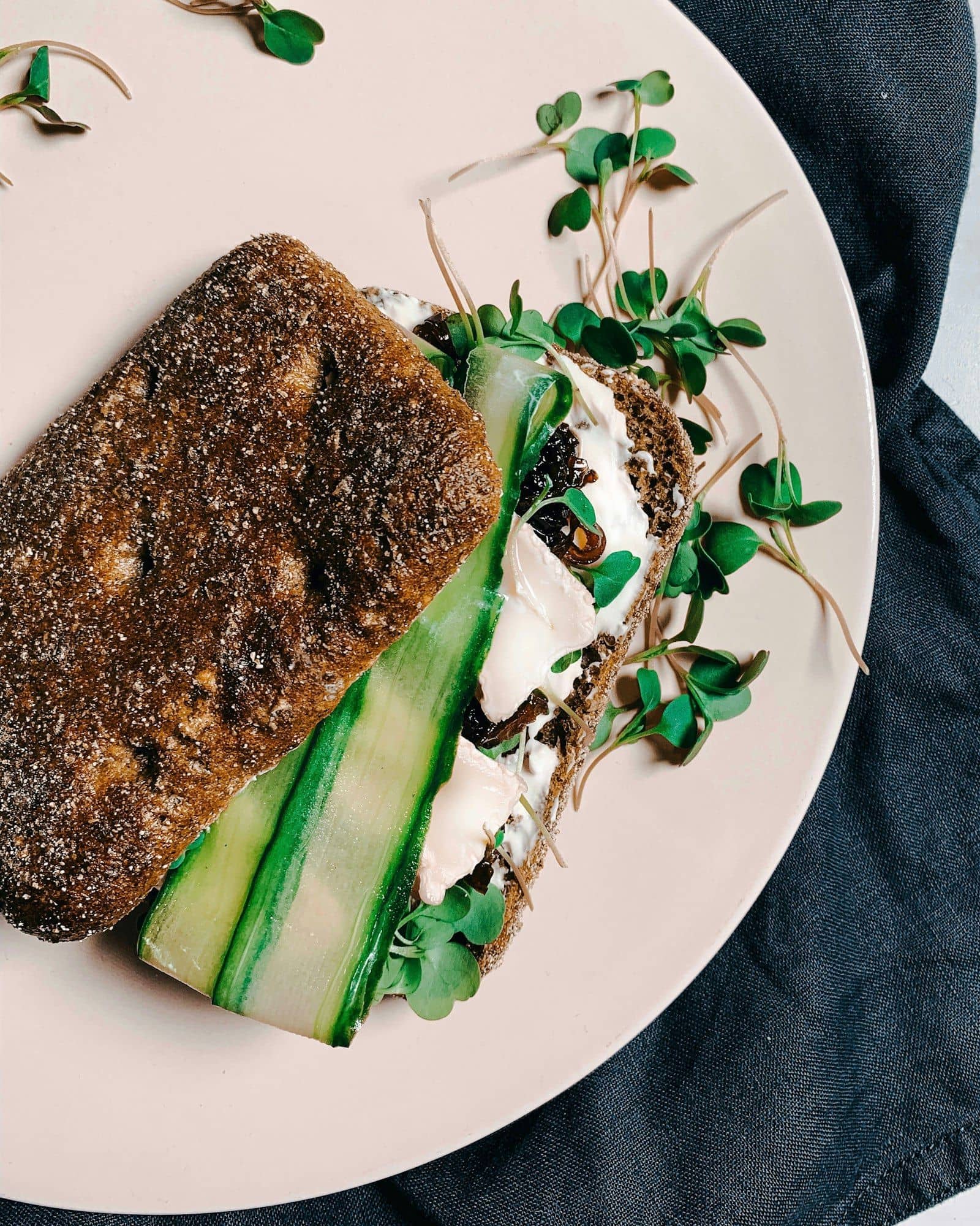 Rye sandwich with cucumber ribbons and cheese, garnished with radish microgreens