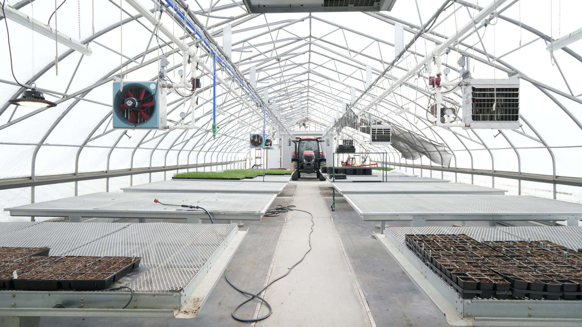 Clean greenhouse interior with circulation fans, heaters and empty benches