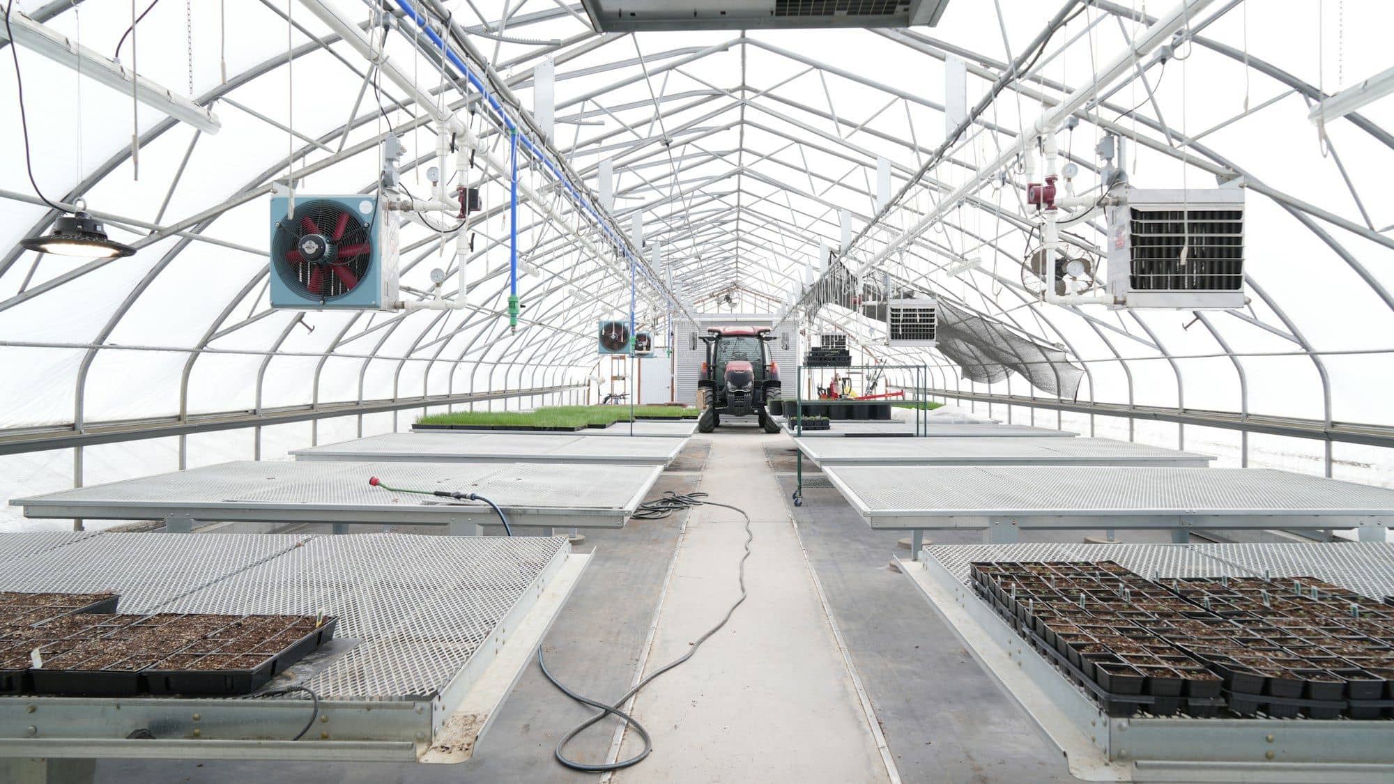 Clean greenhouse interior with circulation fans, heaters and empty benches