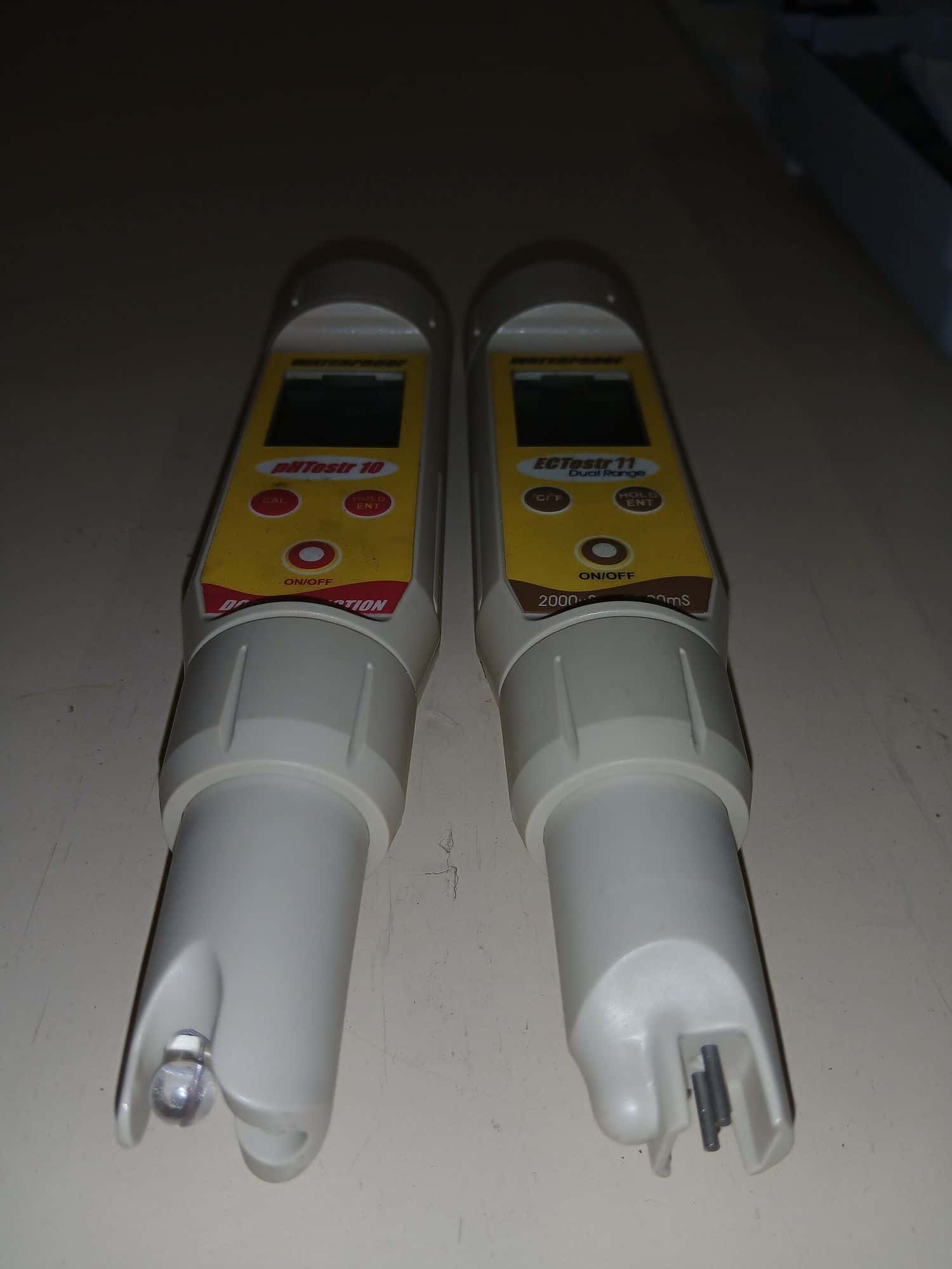 Two handheld testers, one for pH and one for electrical conductivity, lying side by side