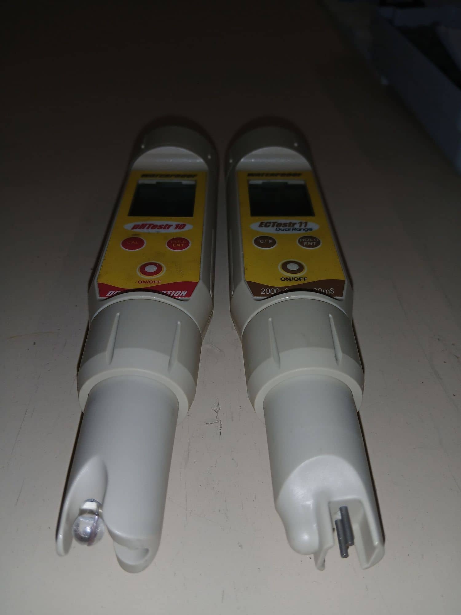 Two handheld testers, one for pH and one for electrical conductivity, lying side by side