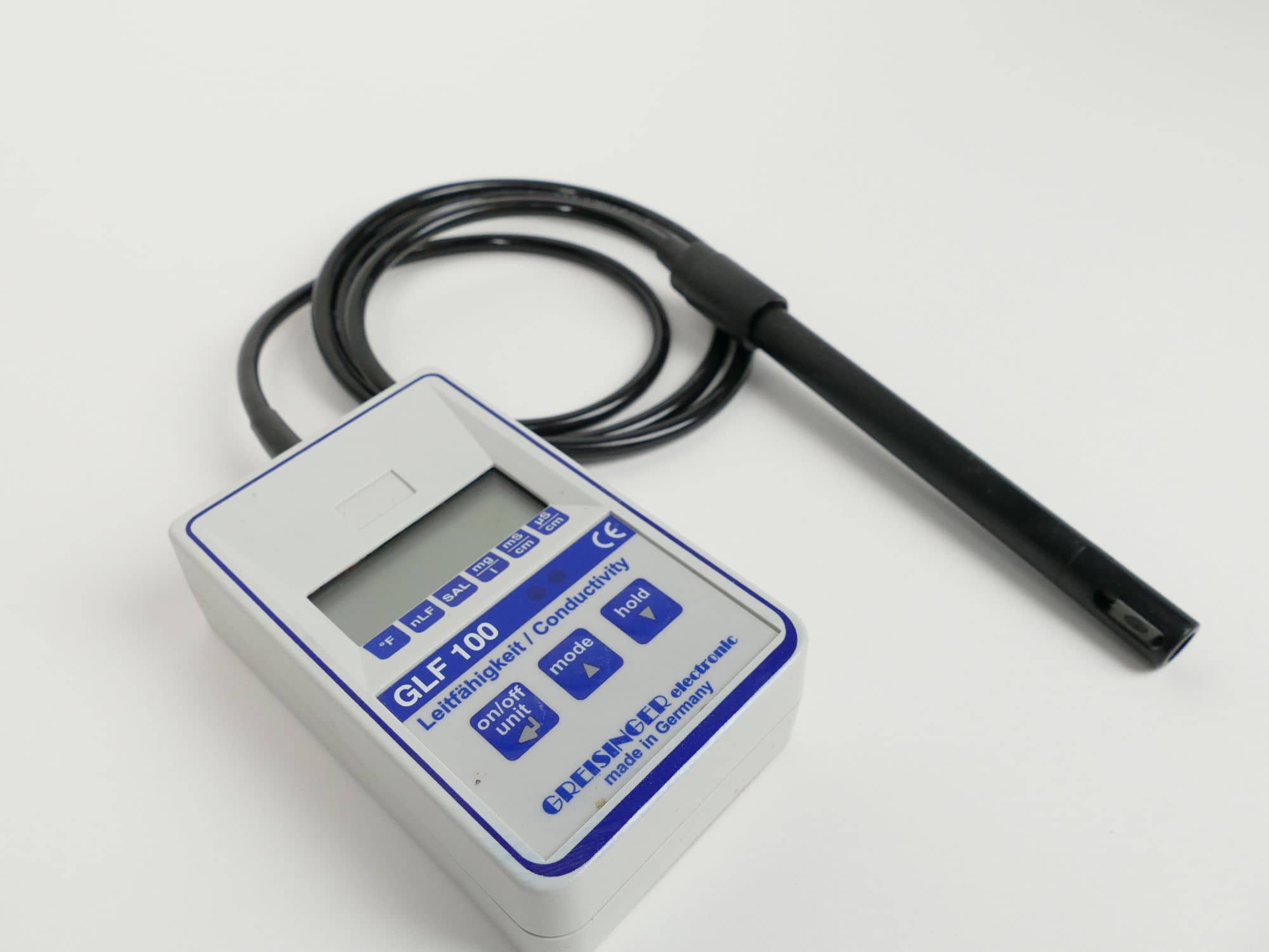 Handheld conductivity meter with a black probe on a white background