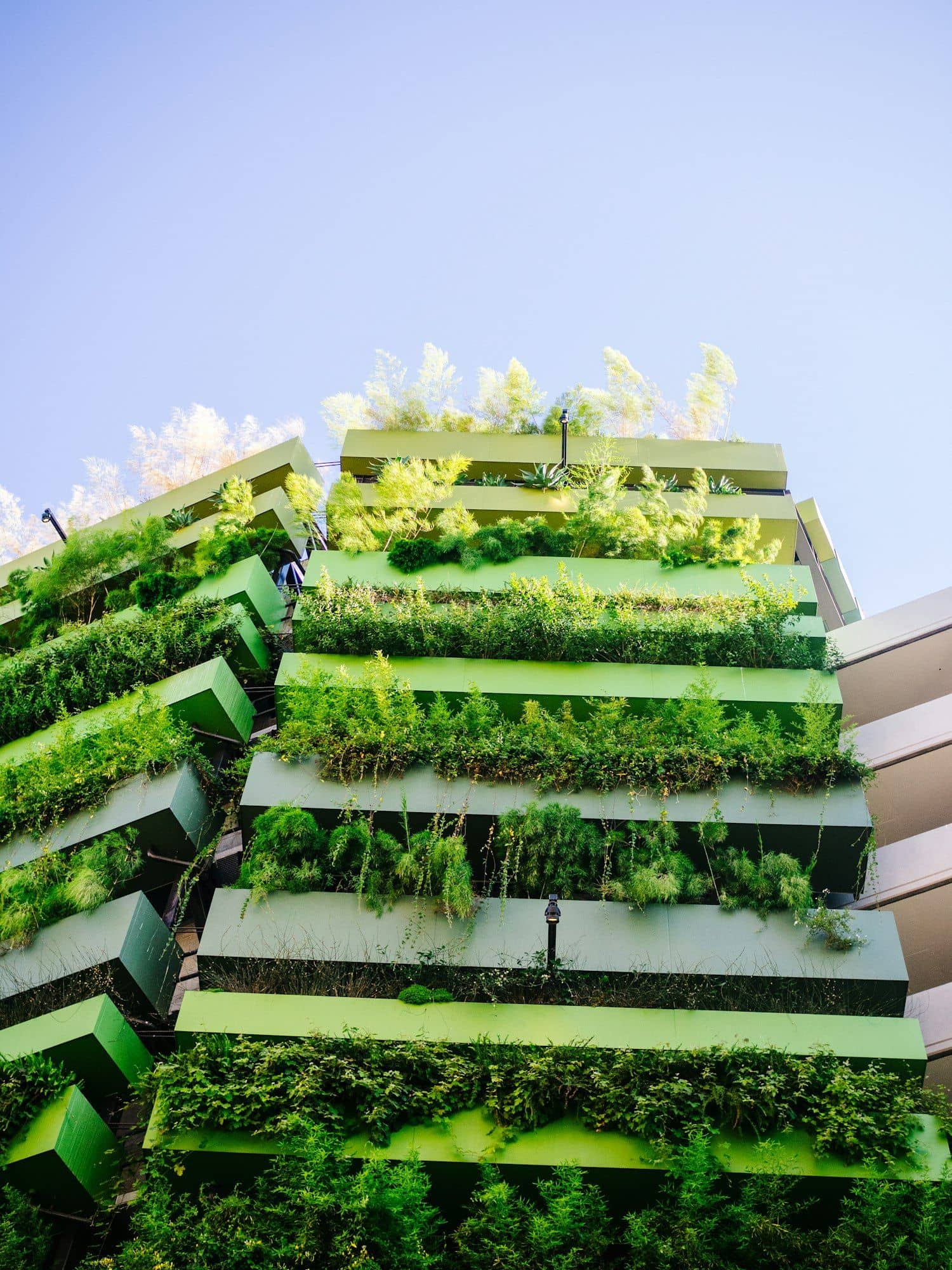 Tall building with planted terraces stepping up its facade against a blue sky